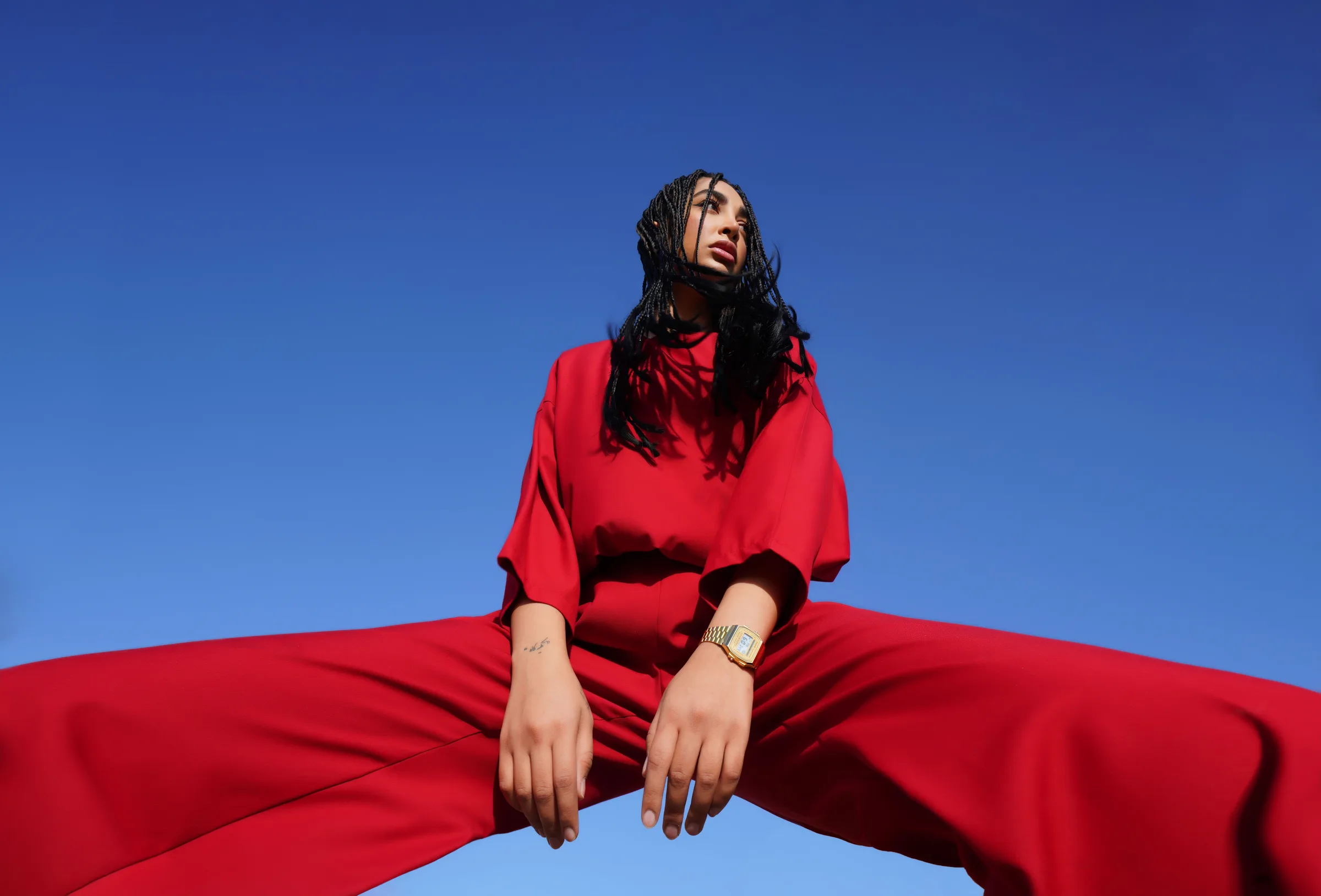 Editorial fashion portrait shot from below against a clear blue sky